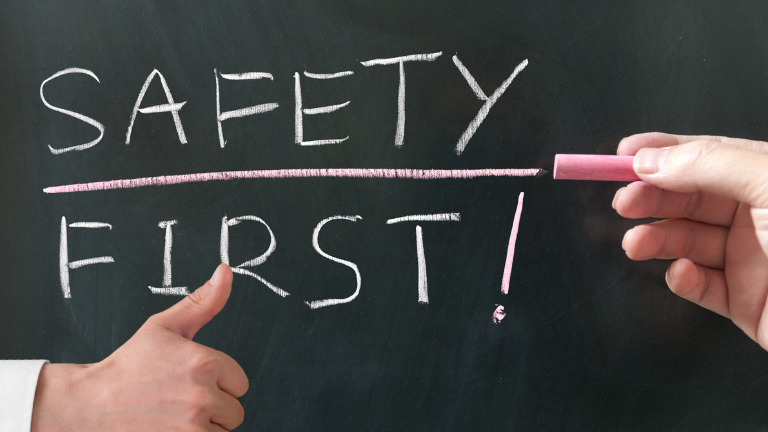 Man writing 'Safety First' on a blackboard with a thumbs up, emphasizing the importance of safety gadgets.